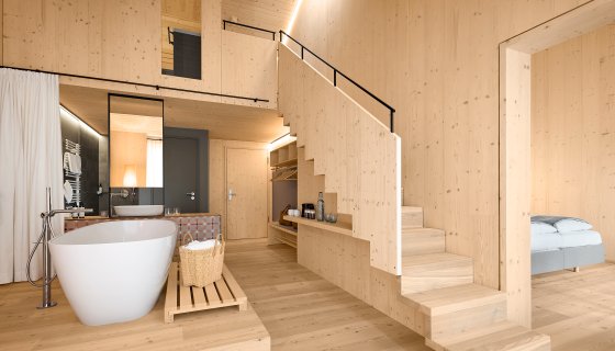 Hochzeitssuite im Kulturhof Stanggass, Zweistöckiges Naturholzzimmer mit Badewanne im Raum und Sauna