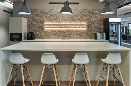 Designküche mit Aufenthaltsbereich inklusive Sitzmöglichkeiten und indirekte Wandbeleuchtung - Infor Stuttgart